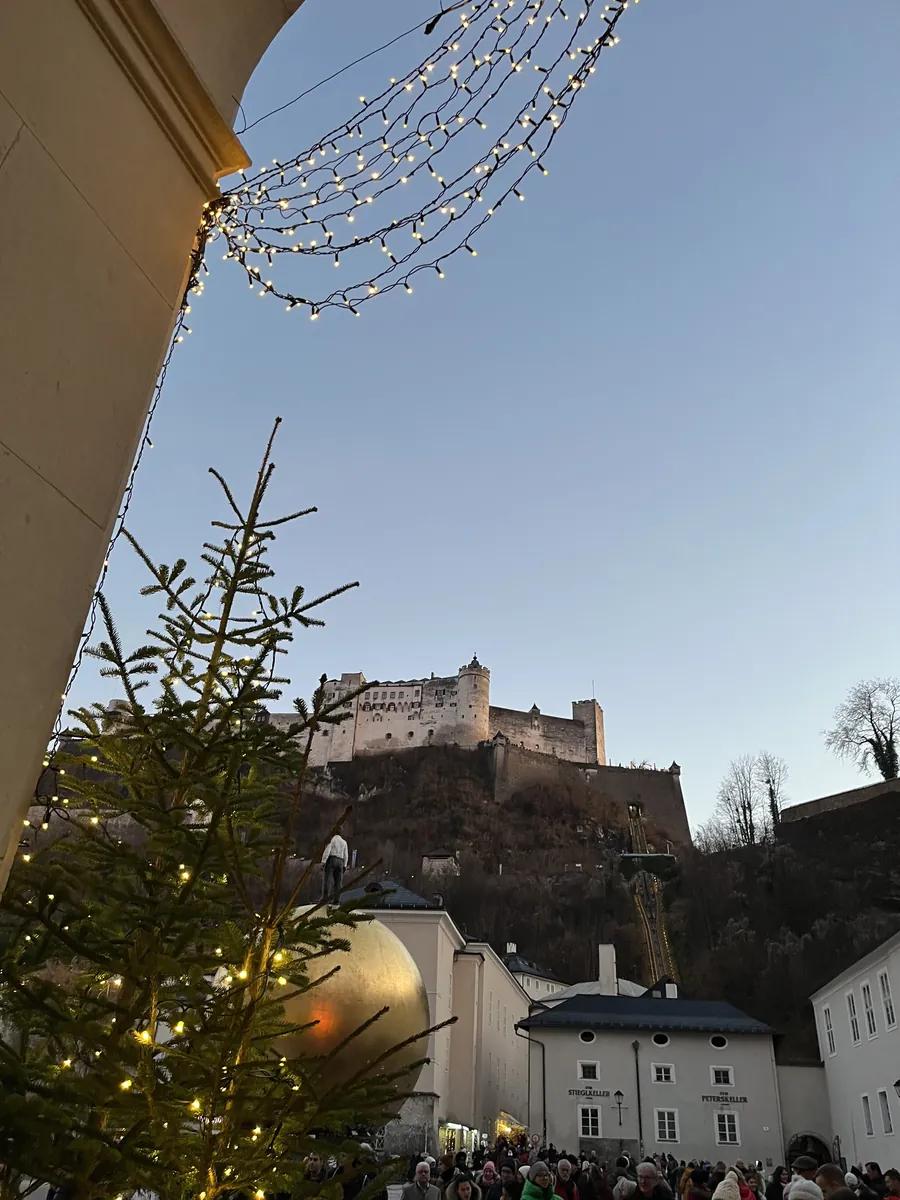 Blick vom Christkindlmarkt in Salzburg auf die Festung Hohensalzburg in der Abenddämmerung