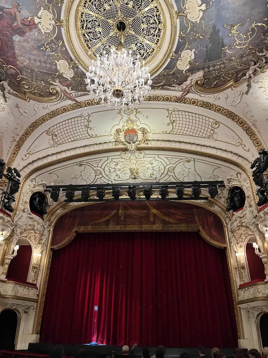 Zuschauerraum des Salzburger Landestheaters mit rotem Vorhang und Kronleuchter